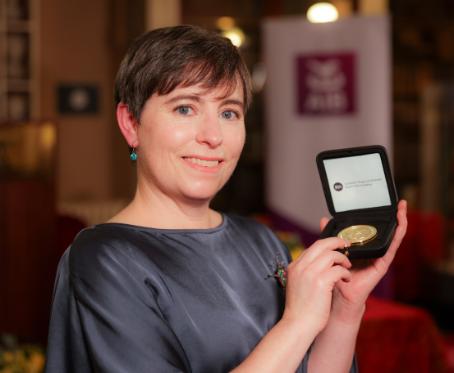 Yvonne stands holding her award medal