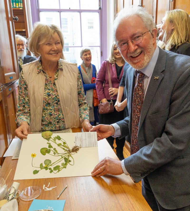 Marcella Campbell, assistant at Trinity's herbarium, examines a plant specimen with Minister Malcolm Noonan