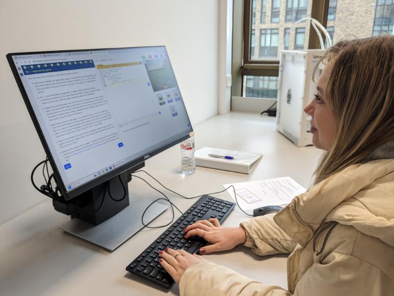 A female student with blond hair works on the Pytch app, on a desktop computer