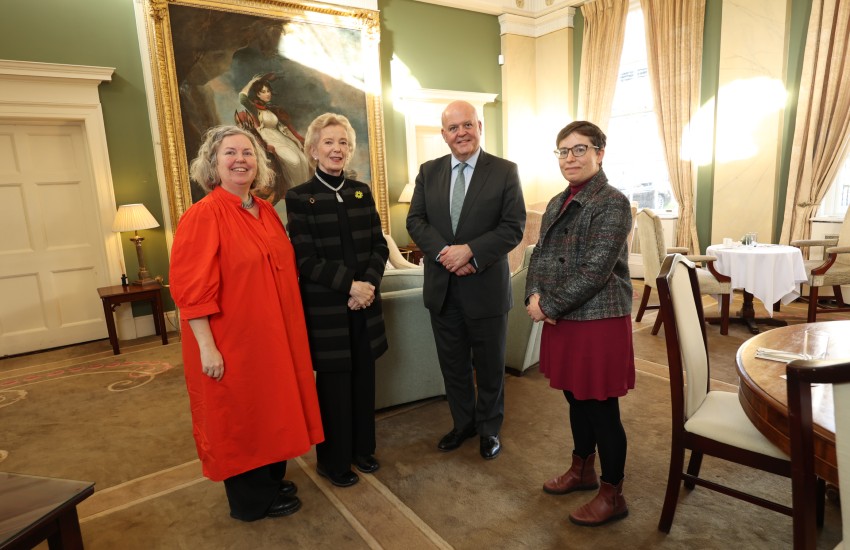 Three women and a man pose in a formal setting