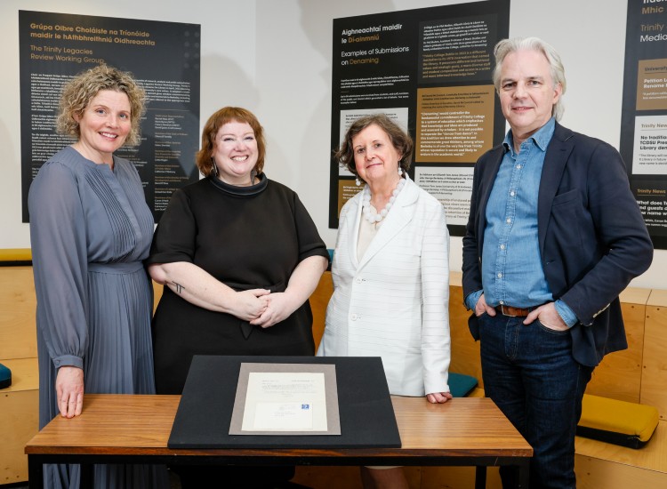 Four people pose with a framed letter