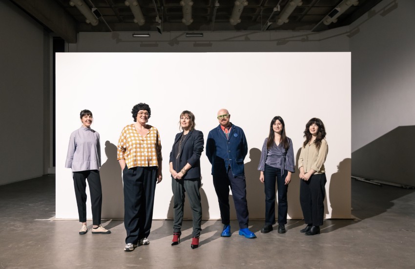 Group of people pose in a plain background