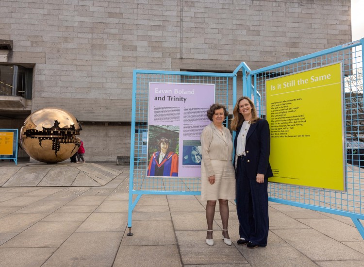 Two women stand before a colourful display
