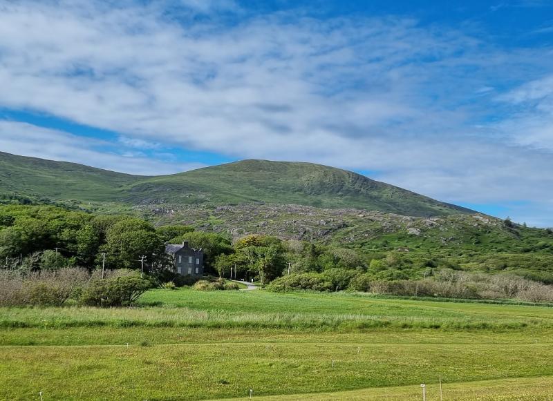 Derrynane House, surrounded by hills, trees, and green fields