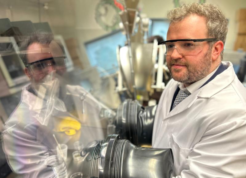 Dr Tian Carey in his lab in the AMBER Centre in Trinity College Dublin, wearing a white lab coat and protective gloves.