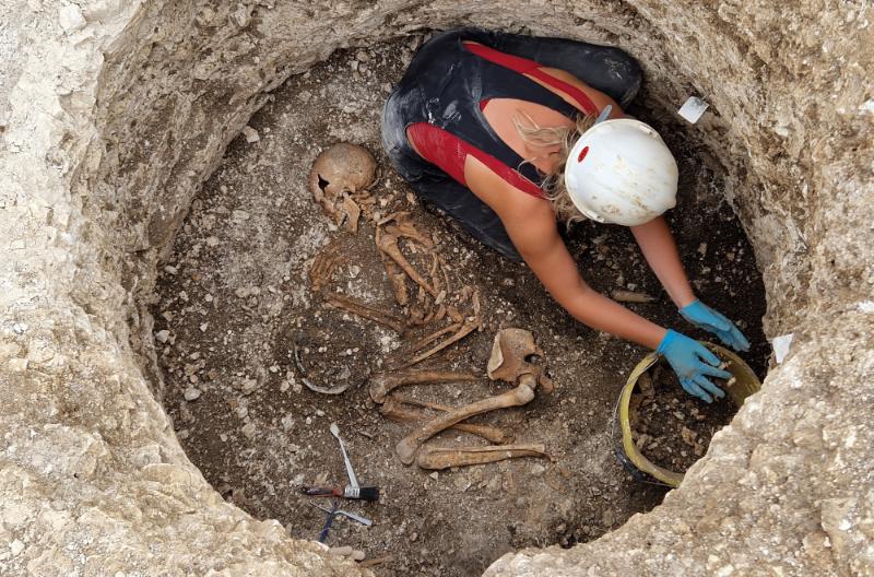 A female researcher, from above, excavating a Late Iron Age Durotriges burial at Winterborne Kingston