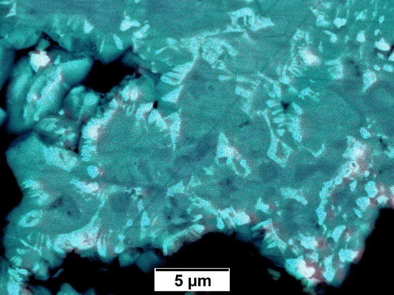 Symplectite textures found in the synthetic rocks containing rare earth carbonate and oxide minerals. The image is a green-blue.