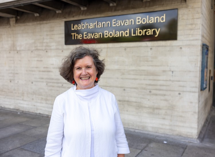Woman dresses in white poses in front of a sign
