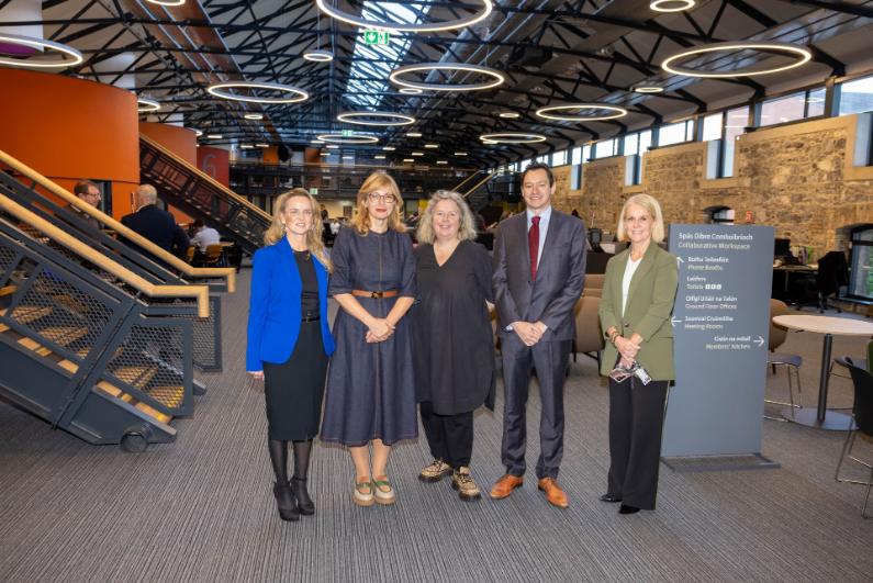 Four women and one man pose in modern building