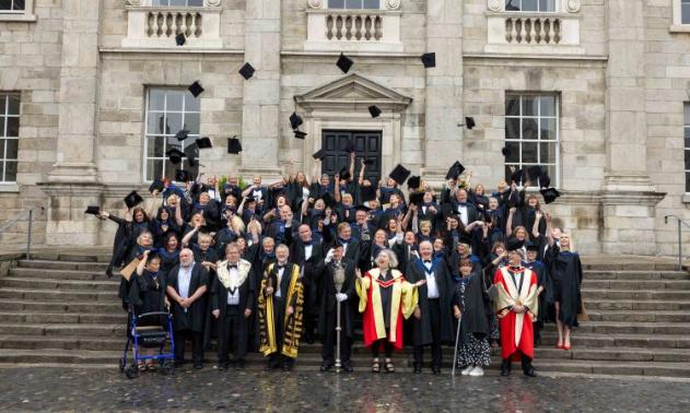 staff members graduating and throwing their caps up on front square