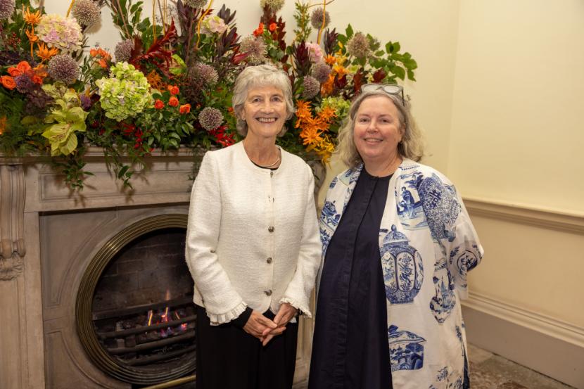 Two women standing in front of an ornamental fireplace