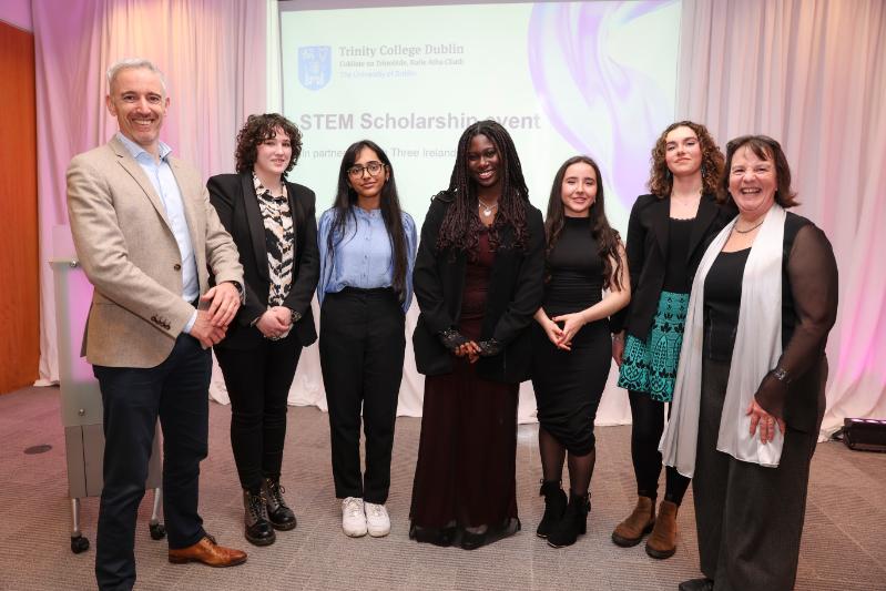Pictured in front of a big screen display are Mark Redmond, Chief People Officer, Three Ireland & UK; scholars Sophie Moore; Alvita Thomas; Joy Aladejanana; Riona Howlin Barman; Rachel Berwick; Prof Sylvia Draper, Dean of the Faculty of STEM
