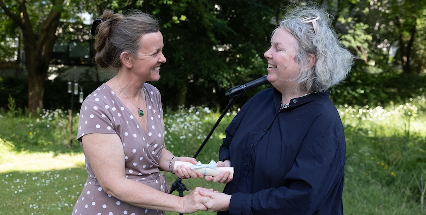 A woman receives an award in a garden