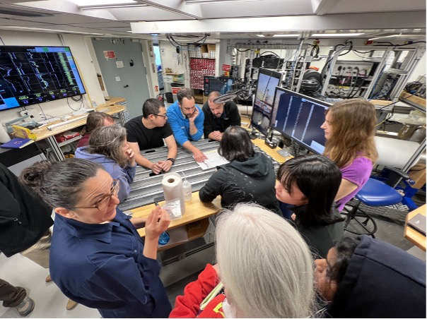 Team discussing preliminary results on the ship at the core table. Image credit: J Field.