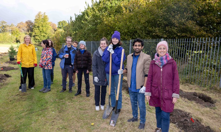 Trinity students and staff line up with spades, ready to plant trees