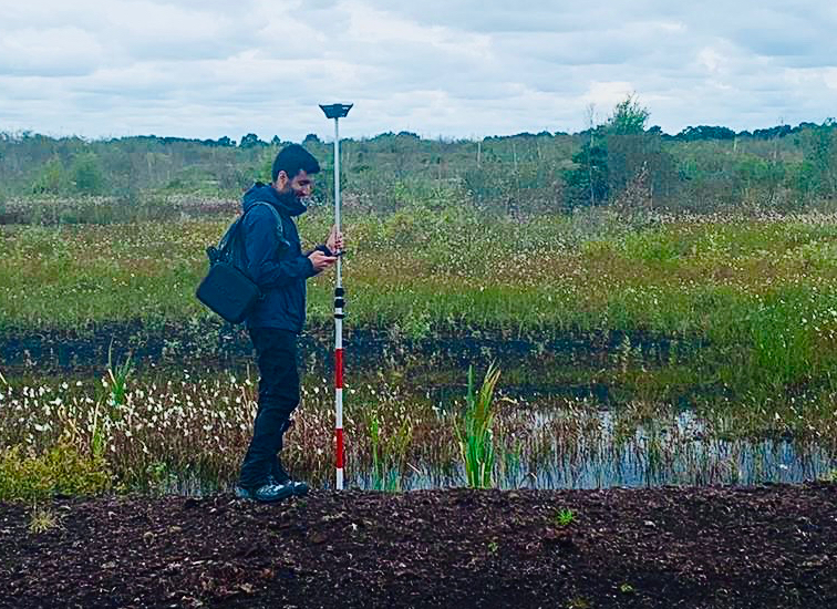 Wahaj Habib collecting samples from a ditch in a field.
