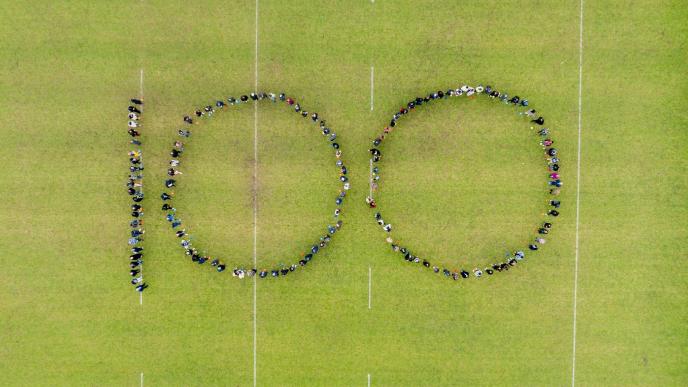 Drone shot of people spelling out 100