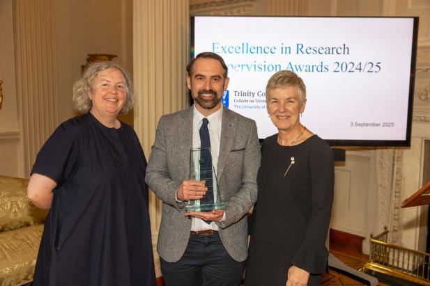 Three people, one holding an award.