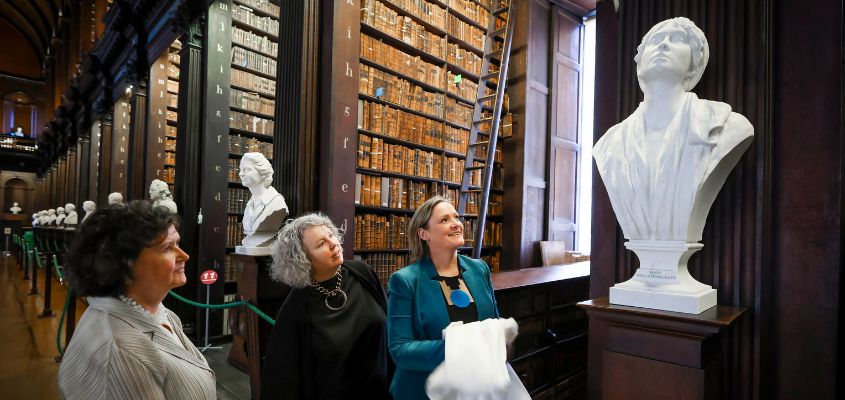 College Librarian, Helen Shenton; Provost, Linda Doyle; and Curator of University Art Collections, Catherine Giltrap stand to the left of the image, looking up at the new sculpture of Mary Wollstonecraft
