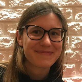 Student with brown hair and glasses smiling