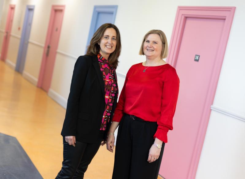 Michelle Spirtos and Sherrie Buckley in a corridor with bright coloured doors behind them
