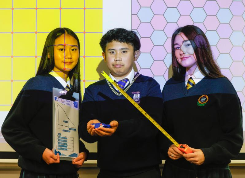 Three students from TAP schools pose with mathematics instruments at Trinity's 