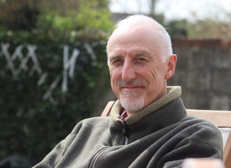 Professor Dan Bradley, smiling in a garden on a sunny day.