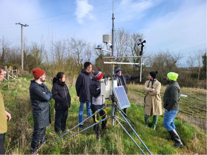 Researchers gather to listen to instructions before planting willow trees.