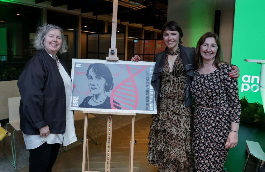 Three women pose with an over-sized stamp