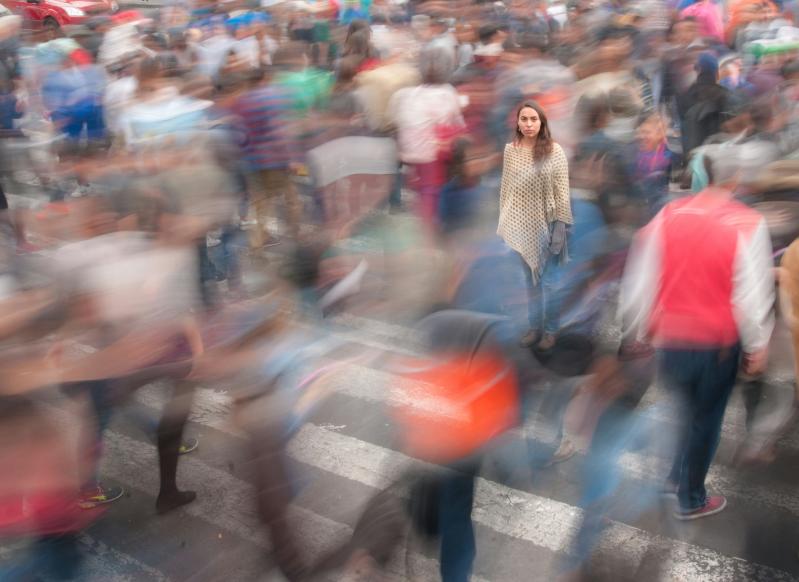 A blurry image of people in a busy town square in Mexico, with one clearly focused young woman with brown hair among the blur