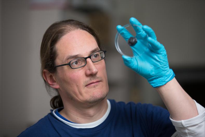Jonathan Coleman wearing a blue lab glove, inspecting some graphene putty
