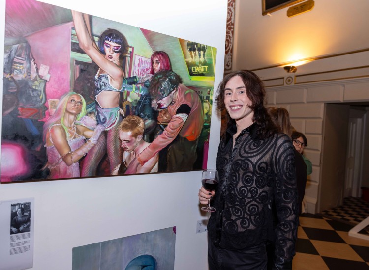 Artist poses beside artwork