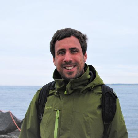 Dr Marius de Leeuw in a green jacket with the sea in the background.