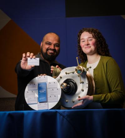 Punit Sobti, MBA graduate and Rachel Kelly, BESS graduate hold the time capsule and an example of the messages