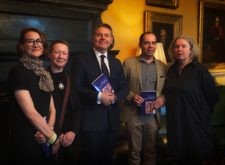 Five people pose with a book