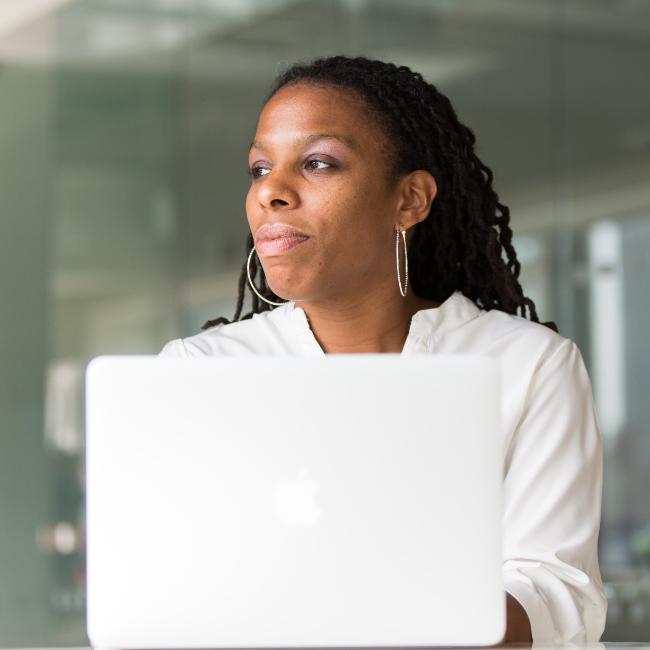 A black woman looking into the distance over a laptop
